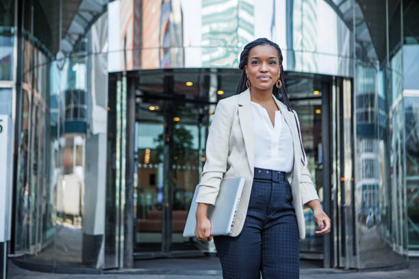 A black ethnicity female professional business woman outdoors on an office complex in the Spring daytime